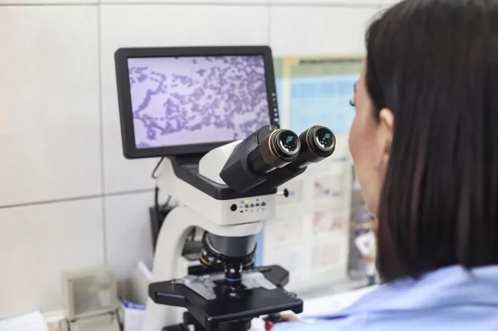 kobieta patrząca na komórki pod mikroskopem